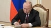 Vladimir Putin signs a document